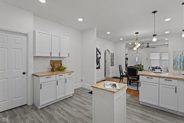 kitchen with butcher block countertops, arched walkways, and light wood finished floors