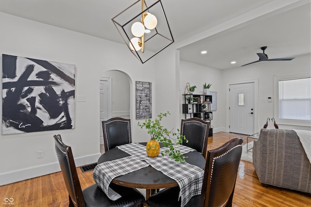 dining area featuring baseboards, visible vents, arched walkways, ceiling fan, and light wood-type flooring