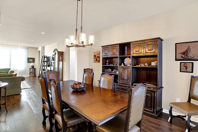 dining room with dark wood finished floors, an inviting chandelier, and baseboards