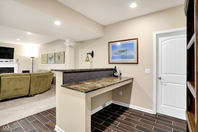 kitchen featuring dark stone countertops, baseboards, wood finish floors, a peninsula, and recessed lighting