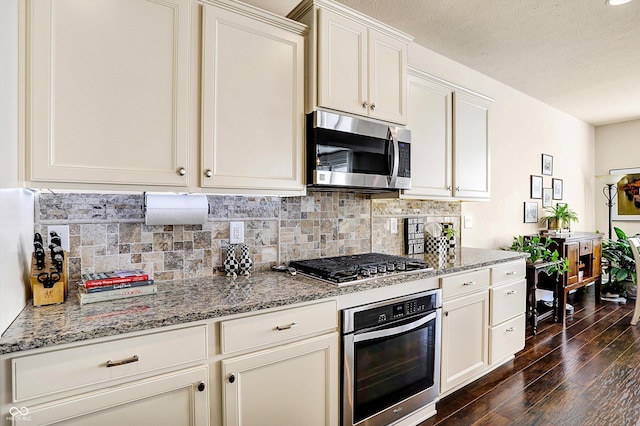 kitchen featuring dark wood-type flooring, light stone counters, backsplash, and stainless steel appliances