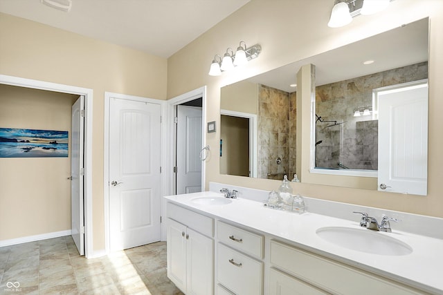 bathroom featuring double vanity, a walk in shower, baseboards, and a sink