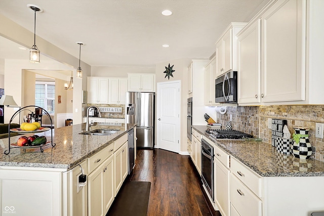 kitchen with dark wood-style floors, a sink, hanging light fixtures, appliances with stainless steel finishes, and backsplash