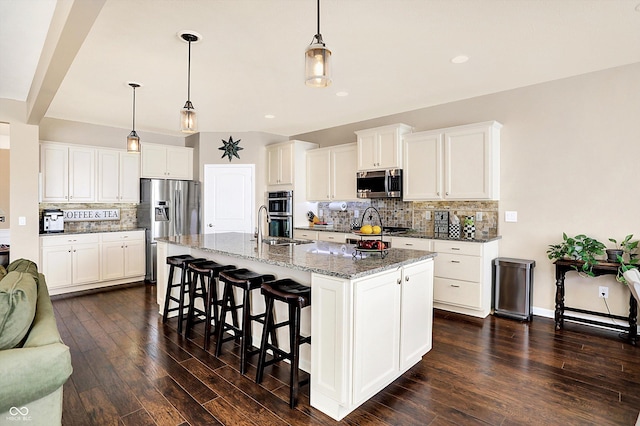 kitchen with a sink, stainless steel appliances, a breakfast bar area, and dark wood finished floors