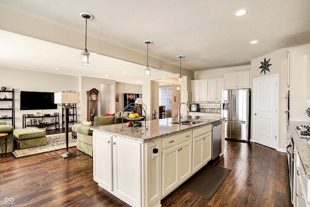 kitchen with open floor plan, appliances with stainless steel finishes, dark wood-type flooring, and a sink