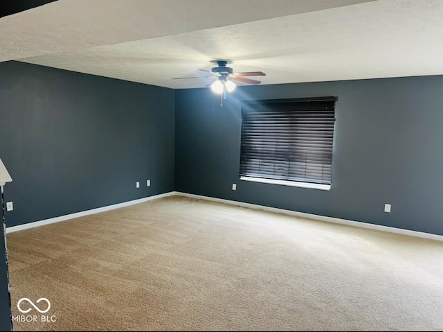 carpeted spare room with a textured ceiling, a ceiling fan, and baseboards