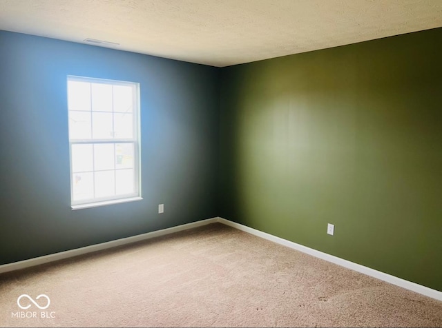 carpeted empty room with visible vents, a textured ceiling, and baseboards