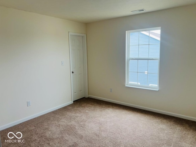 spare room with a wealth of natural light, carpet flooring, visible vents, and baseboards