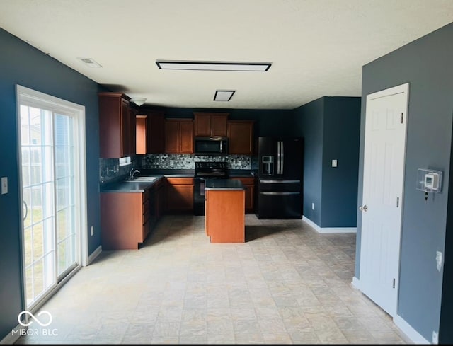 kitchen with a center island, backsplash, a sink, black appliances, and baseboards