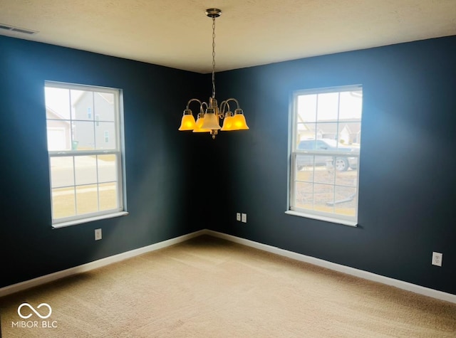 spare room with an inviting chandelier, visible vents, baseboards, and carpet flooring