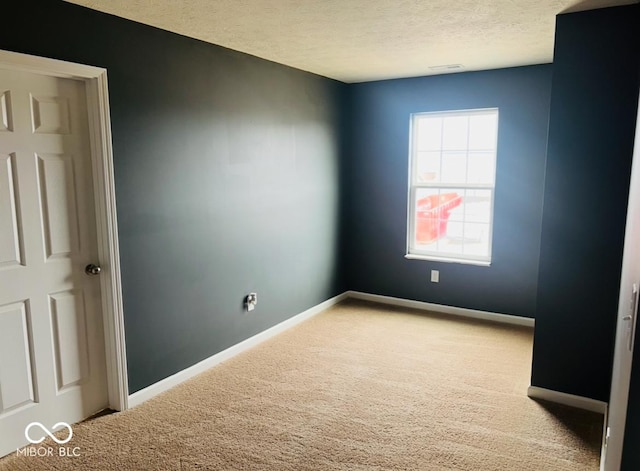 carpeted spare room featuring visible vents, a textured ceiling, and baseboards