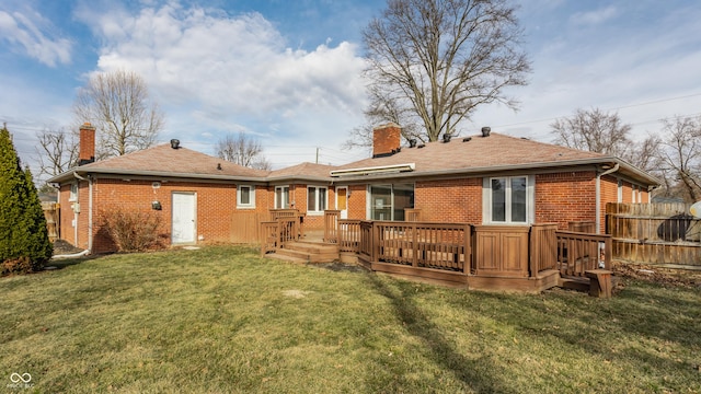 rear view of house featuring a deck, brick siding, a lawn, and a chimney