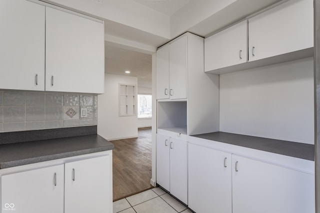 kitchen featuring light tile patterned flooring, recessed lighting, white cabinetry, backsplash, and dark countertops