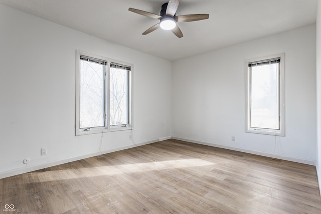 spare room featuring light wood-type flooring, a healthy amount of sunlight, and baseboards