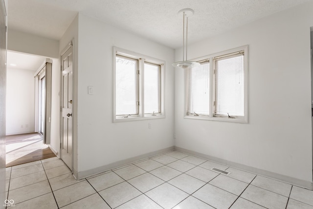 unfurnished dining area featuring light tile patterned floors, visible vents, and a textured ceiling