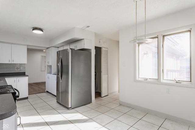 kitchen featuring dark countertops, white cabinetry, stainless steel fridge with ice dispenser, and light tile patterned floors