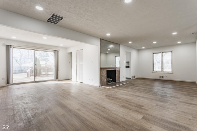 unfurnished living room with recessed lighting, wood finished floors, visible vents, and a high end fireplace