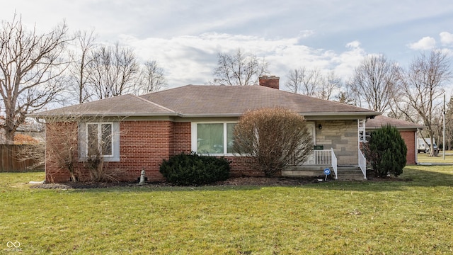 view of front of house featuring brick siding, a chimney, and a front lawn