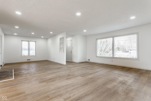 empty room with light wood-style floors, visible vents, and recessed lighting