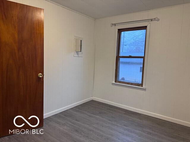 unfurnished room featuring baseboards and dark wood-style flooring