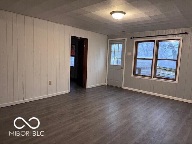 empty room with dark wood-type flooring and baseboards