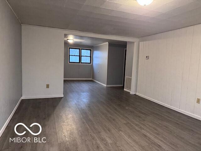 spare room with dark wood-style floors, visible vents, and baseboards