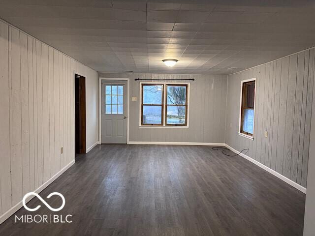 spare room featuring baseboards and dark wood finished floors