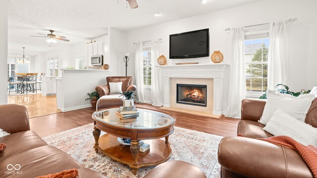 living room with ceiling fan, baseboards, wood finished floors, and a fireplace with flush hearth