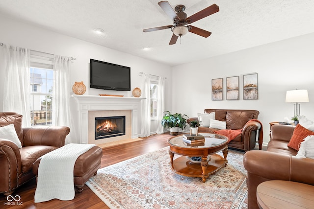 living room with a fireplace with flush hearth, a textured ceiling, and wood finished floors