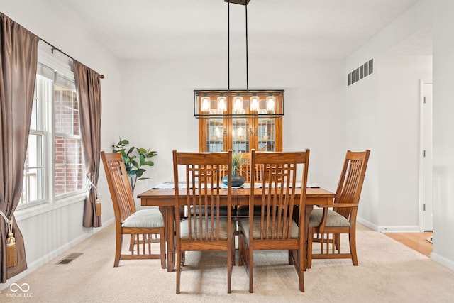 dining room featuring light carpet, baseboards, and visible vents