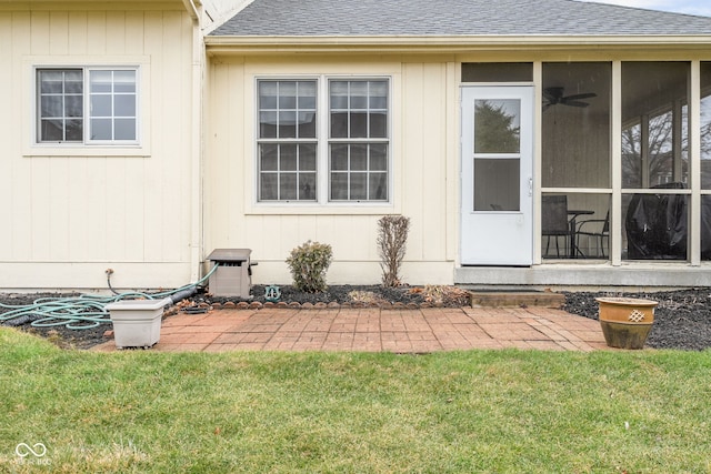 view of exterior entry featuring a shingled roof and a lawn