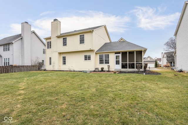 rear view of house featuring a yard, a chimney, fence, and a sunroom