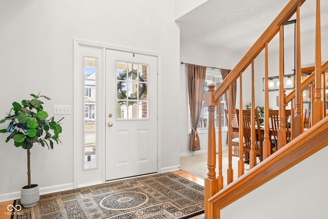 foyer entrance featuring baseboards, stairway, and a healthy amount of sunlight