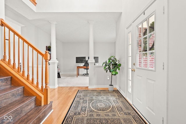 entrance foyer with stairs, baseboards, wood finished floors, and ornate columns