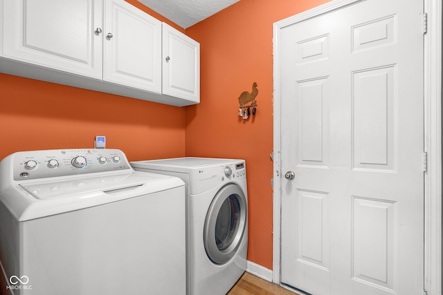 washroom with cabinet space, a textured ceiling, baseboards, and separate washer and dryer