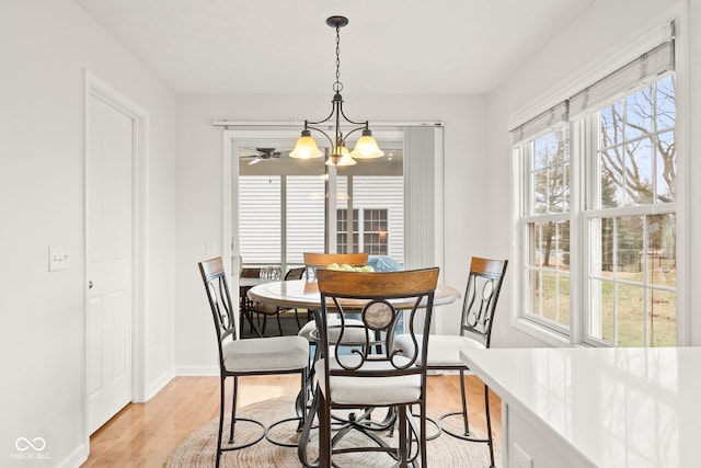 dining room featuring light wood-style floors, baseboards, and a notable chandelier