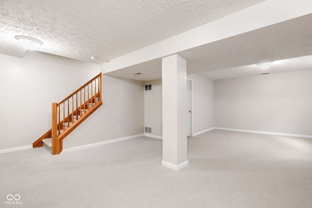 finished basement with visible vents, carpet flooring, stairway, and baseboards