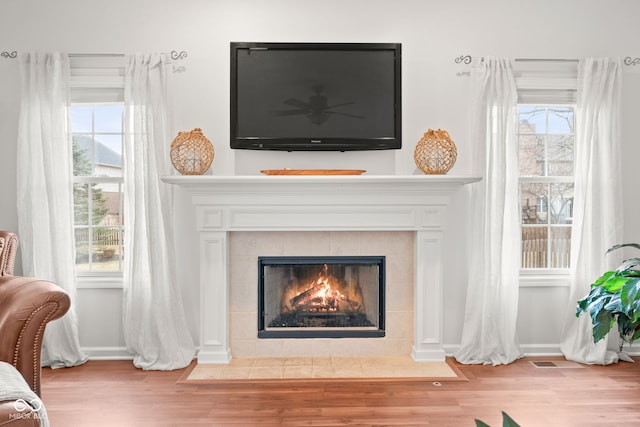 room details featuring a tile fireplace, baseboards, and wood finished floors