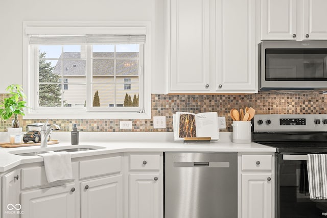 kitchen featuring white cabinets, decorative backsplash, stainless steel appliances, and a sink