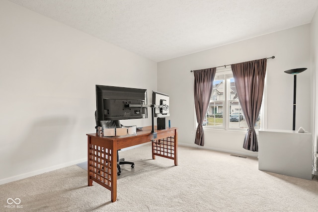 carpeted office with baseboards, visible vents, and a textured ceiling