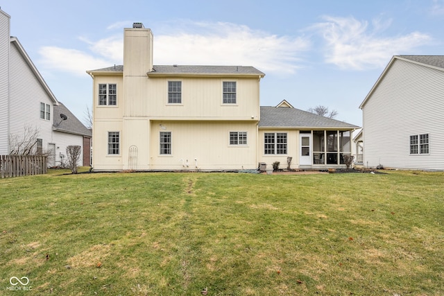 back of house featuring a sunroom, a lawn, a chimney, and fence