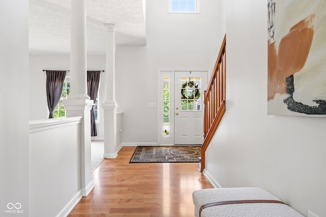 11866 Weathered Edge Dr, Fishers, IN 46037 - foyer entrance featuring ornate columns, light wood finished floors, stairs, baseboards, and a textured ceiling