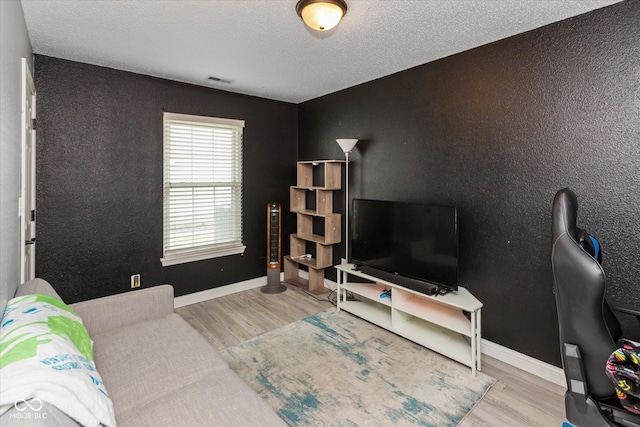 living area featuring a textured ceiling, baseboards, and wood finished floors