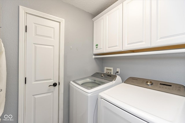 laundry room with a textured ceiling, separate washer and dryer, and cabinet space