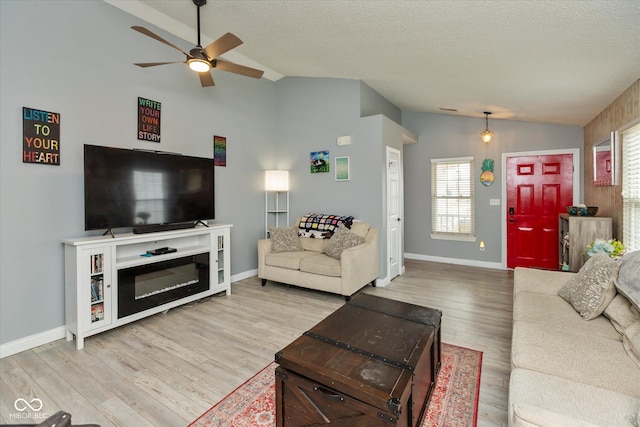 living area with lofted ceiling, ceiling fan, a textured ceiling, and wood finished floors