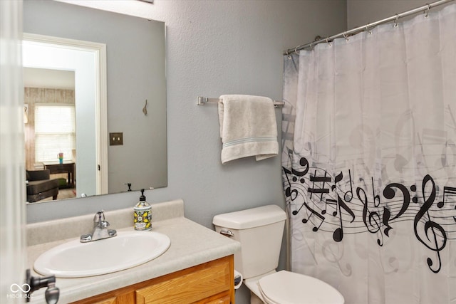 bathroom with toilet, a shower with curtain, a textured wall, and vanity