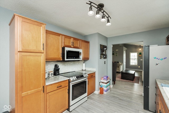 kitchen featuring light countertops, light wood-style flooring, backsplash, electric range, and freestanding refrigerator