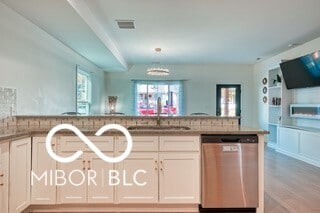 kitchen featuring visible vents, open floor plan, a sink, light wood-type flooring, and dishwasher