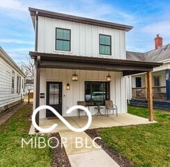 back of house featuring covered porch, board and batten siding, and a yard