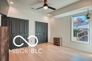 unfurnished bedroom with baseboards, multiple closets, wood finished floors, and recessed lighting